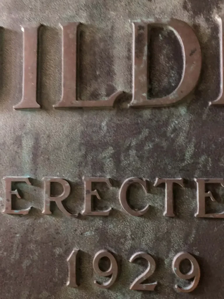 Corner of the Gulf Building plaque showing the banded bronze border and a countersunk mounting hole